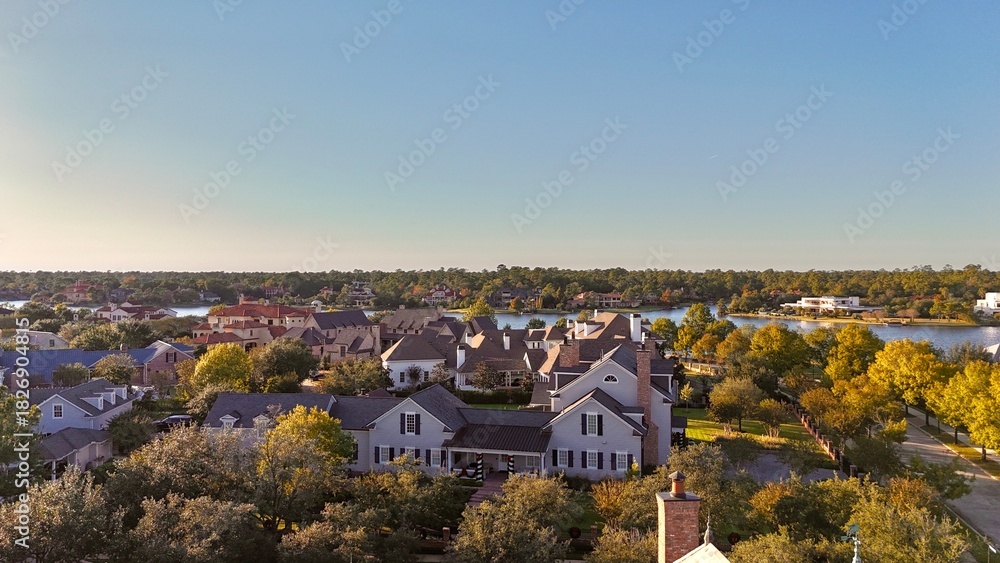Obraz premium Aerial view of large mansion houses with swimming pool, in affluent neighborhood by Woodlands lake, Houston, Texas, expensive suburban homes surrounding by lush green trees, USA