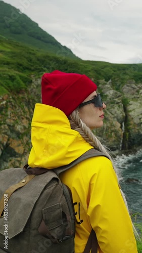 A Stylish Outdoor Enthusiast in Bright Yellow Rain Gear and Red Beanie, Captured Against a Stunning Natural Landscape by the Sea