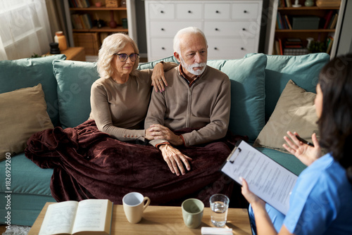 Mature couple talking with a female nurse during her home visit.