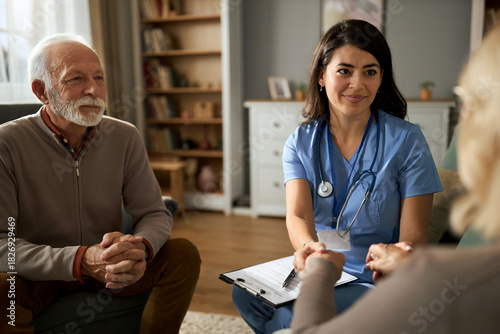Female doctor holding hands with her patient during home visit.