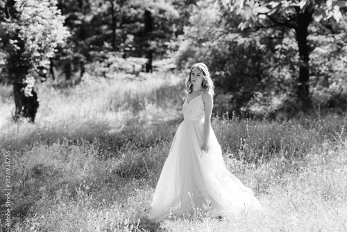 Blonde bride in a light coral dress in a green forest