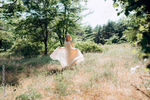 Blonde bride in a light coral dress in a green forest