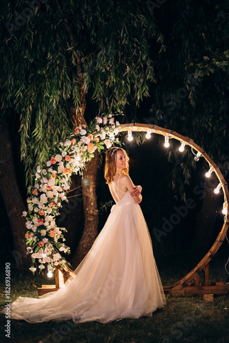 blonde bride in a light coral dress against the backdrop of an evening round arch