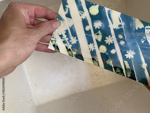 Woman holding exposed blueprint under running, cold water.  