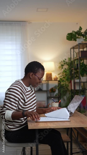 African woman working and writing from her home office late at night