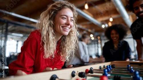 Group of people playing foosball in an office setting.