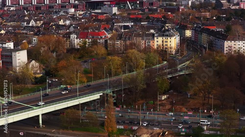 Aerial footage revealing urban landscape of Cologne, Germany. Cityscape includes residential areas, bustling streets, and iconic Lanxess Arena
