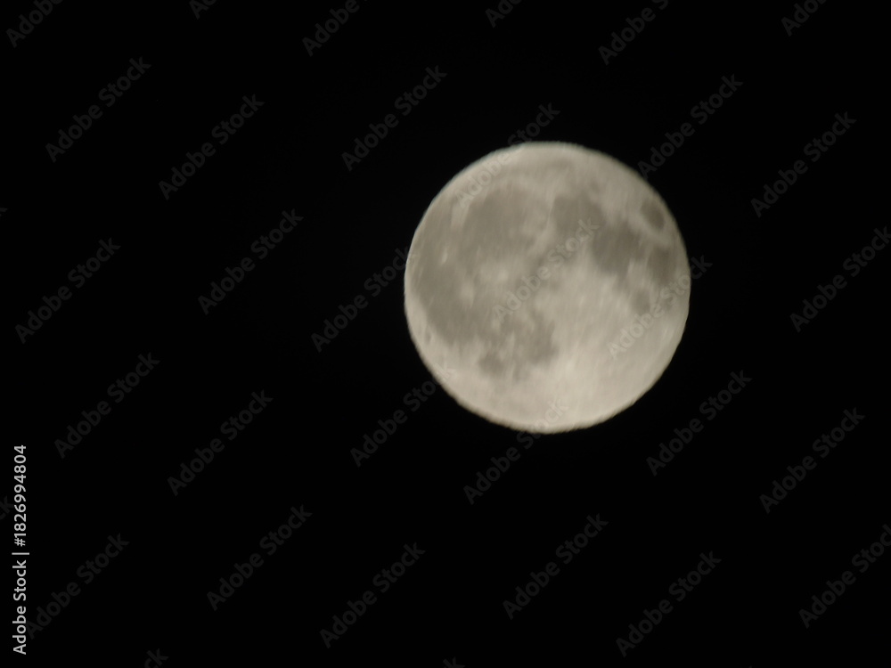 Fototapeta premium Genova, Italy - 07/09/2025: An amazing photography of the full moon over the city of Genova by night with a great clear and blue sky in the background and some stars.