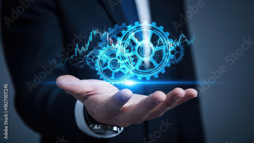 Hand holding glowing blue gears and financial data chart technology