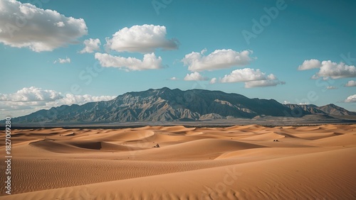 Fototapeta Naklejka Na Ścianę i Meble -  Desert landscape with sand dunes and mountain range under a sky with clouds.