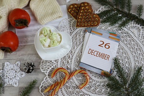 December 26 Calendar: The number 26 and the month's name in English on a decorative calendar surrounded by a lace napkin and Christmas sweets