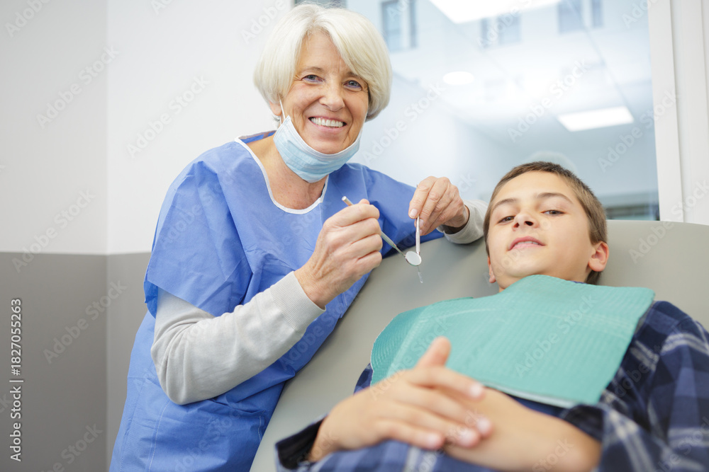 Obraz premium senior female dentist with a kid patient