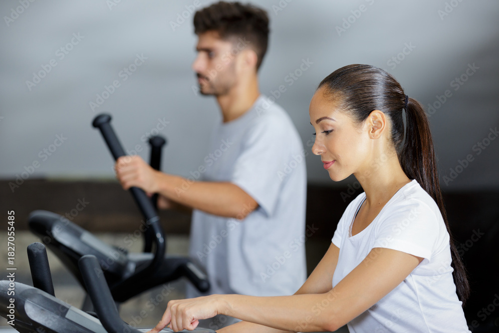 Obraz premium man and woman walking on treadmills in modern gym