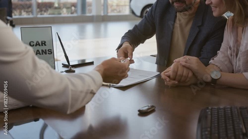 Close up shot of unrecognizable car salesman handing contract to couple of clients while sitting at desk and signing contract buying new car, copy space