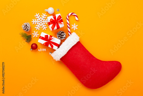 Christmas sock with gifts and decoration on color background, top view