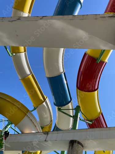 Colorful water slides against a clear blue sky viewed from underneath
