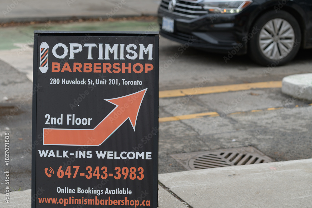 Fototapeta premium sidewalk sign of Optimism Barbershop located at 280 Havelock St unit 201, Toronto