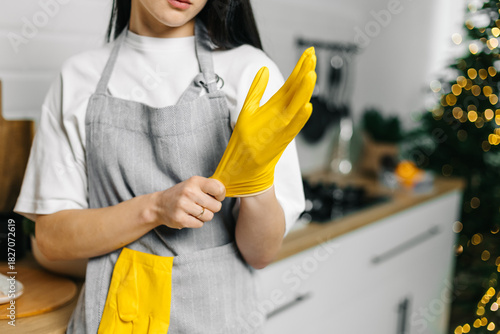 Close up hands putting on yellow rubber glove for kitchen cleaning
