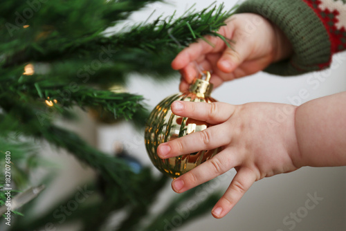 Close up shot of baby playing with a christmas bauble. Copy space, background.