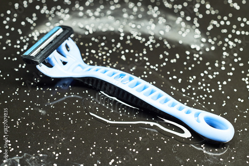 Close-up of a disposable razor on a wet black surface.