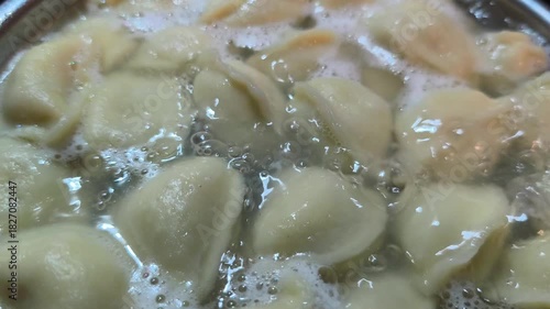 Dumplings boiling in a pot with visible boiling water on stove, cooking process in kitchen