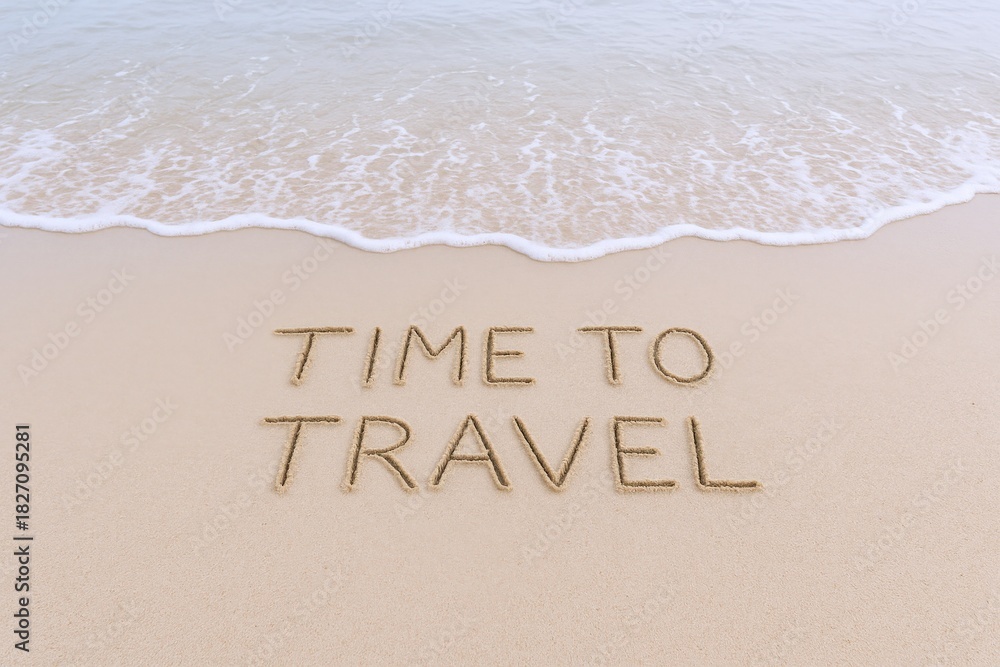 Fototapeta premium Time to Travel Message Written on Sandy Beach Shoreline with Gentle Wave Coming In, Travel Concept