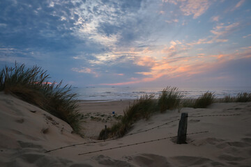 Foto auf Acrylglas Nordsee Sunset view through dune path toward the North Sea at Wassenaarse Slag, Netherlands  © Menyhert