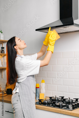 Woman cleaning kitchen range hood with cloth