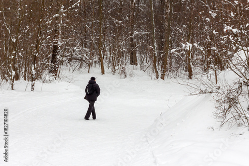 Senior man walking on snow trail inter forest
