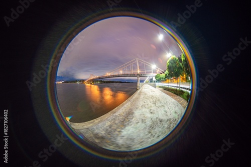 Foto Twilight scene of a body of water with bridge under cloudy sky, shot with fishey