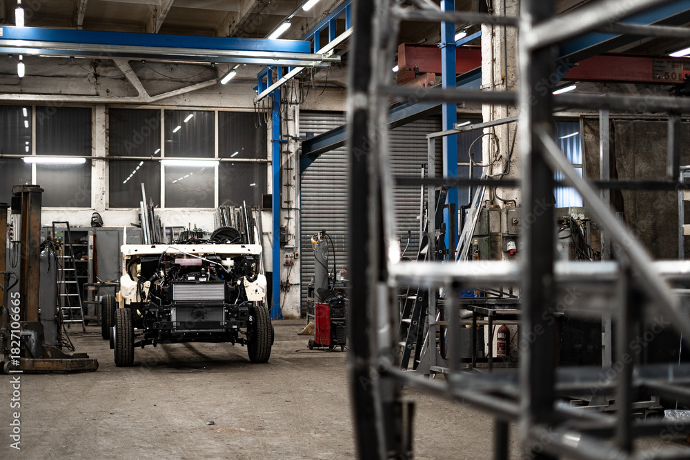 Fototapeta premium Industrial workshop with the metal frame construction of a bus or RV. Large vehicle chassis in fabrication, showcasing manufacturing, engineering, and assembly environment.