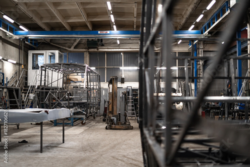 Industrial workshop with the metal frame construction of a bus or RV. Large vehicle chassis in fabrication, showcasing manufacturing, engineering, and assembly environment.