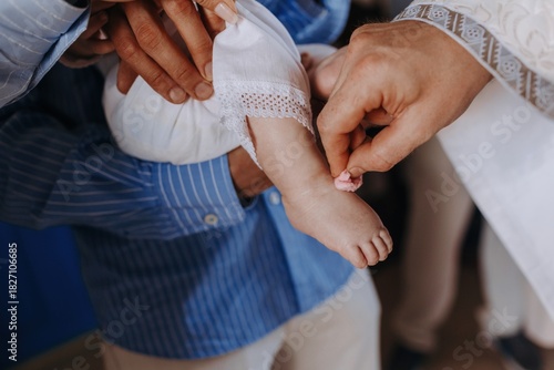 Photos Priest anointing a baby's foot with holy oil using cotton during a baptism ceremony