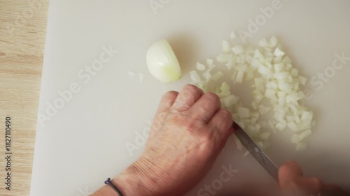 Watch as an individual skillfully chops onions on a clean cutting board in a warm