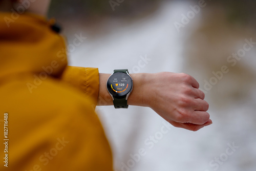 Slika na platnu Close-up of an athlete checking heart rate on a smartwatch during a winter workout