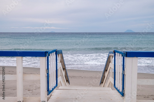 Wooden fence with a staircase leading to a beach overlooking the Mediterranean Sea along the Sicilian coast	