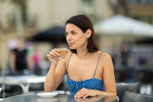 Canvas Print Young woman in summer dress drinking fresh coffee in street cafe
