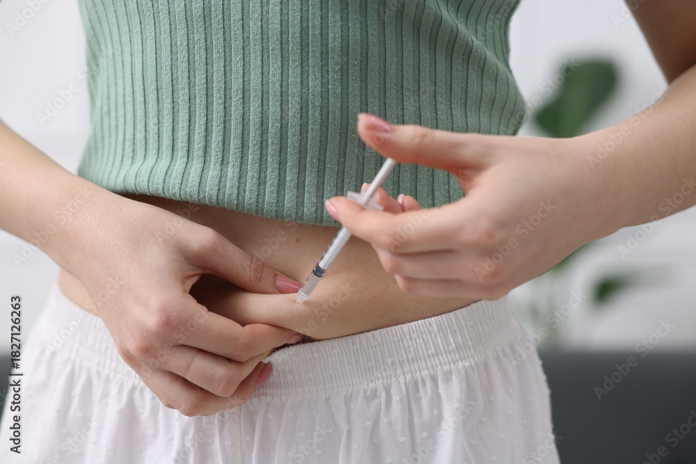 Naklejka premium In vitro fertilisation. Woman making injection into her belly indoors, closeup