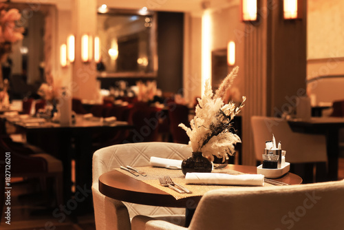 Photography Elegant, reserved table in a dimly lit luxury restaurant with a dried floral centerpiece, set for fine dining