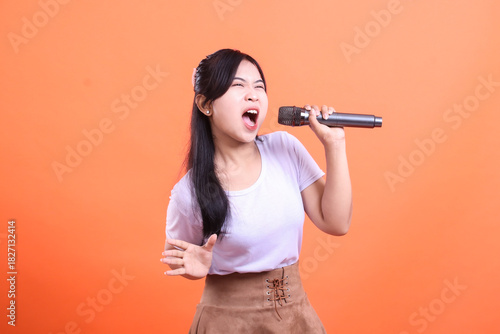 Εκτύπωση καμβά A young asian woman singing with a microphone in her hand with passionate expres