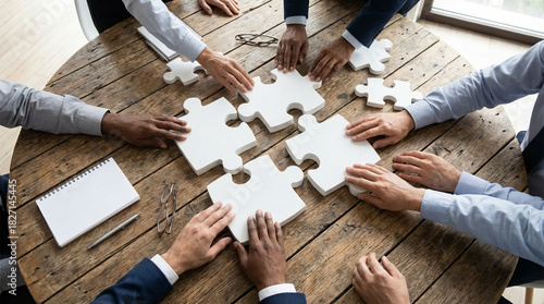 Teamwork and collaboration as a diverse business team joins puzzle pieces to find a corporate strategy and solution.