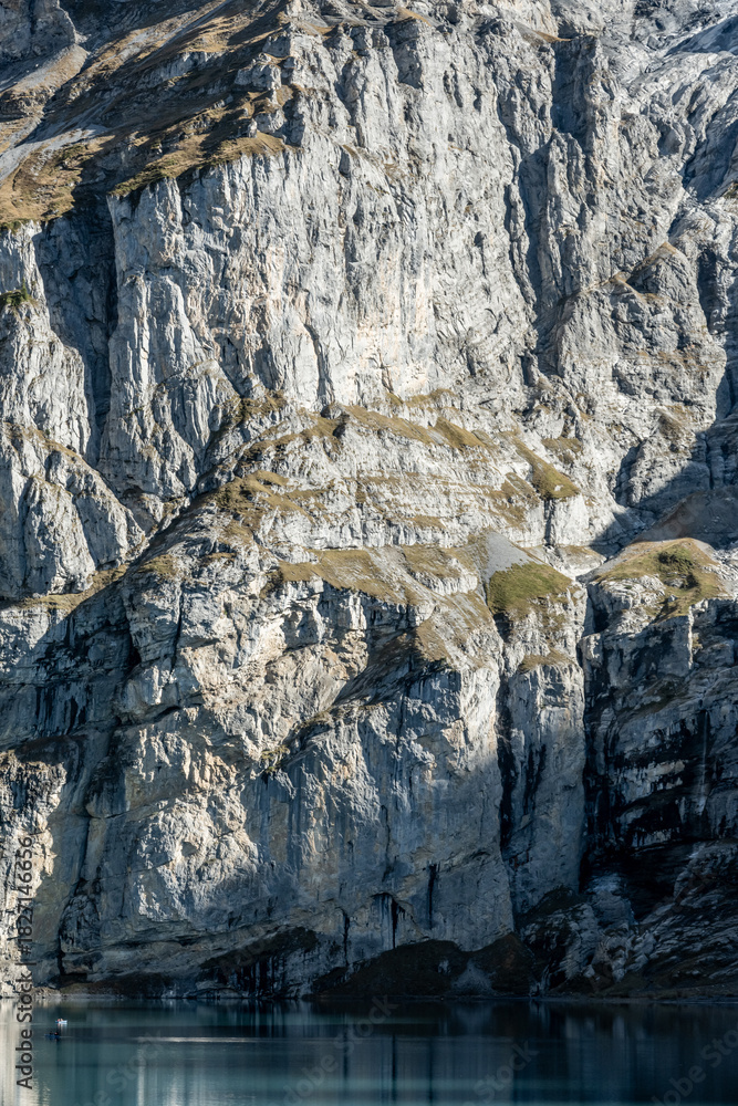 Naklejka premium Tall Cliffs Catch Shadow And Light Over Oeschinen Lake