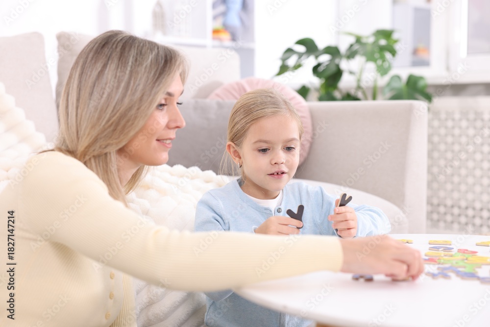 Obraz premium Mother teaching her daughter alphabet at white table indoors