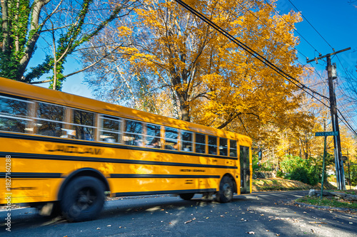 Yellow school bus travels through autumn colors in Wilton Connecticut