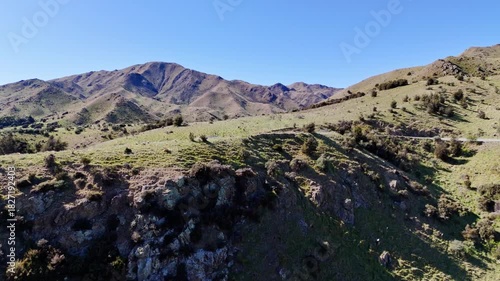 Aerial panorama of a scenic mountain range featuring lush green hills and a wide clear blue sky
