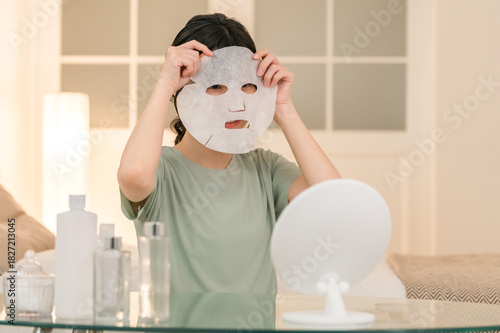 Young Asian woman using face pack at night (skin care, sheet mask, night care)
