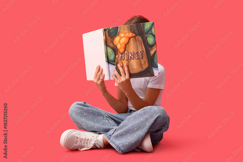 Naklejka premium Cute little girl reading fairy tale book on red background
