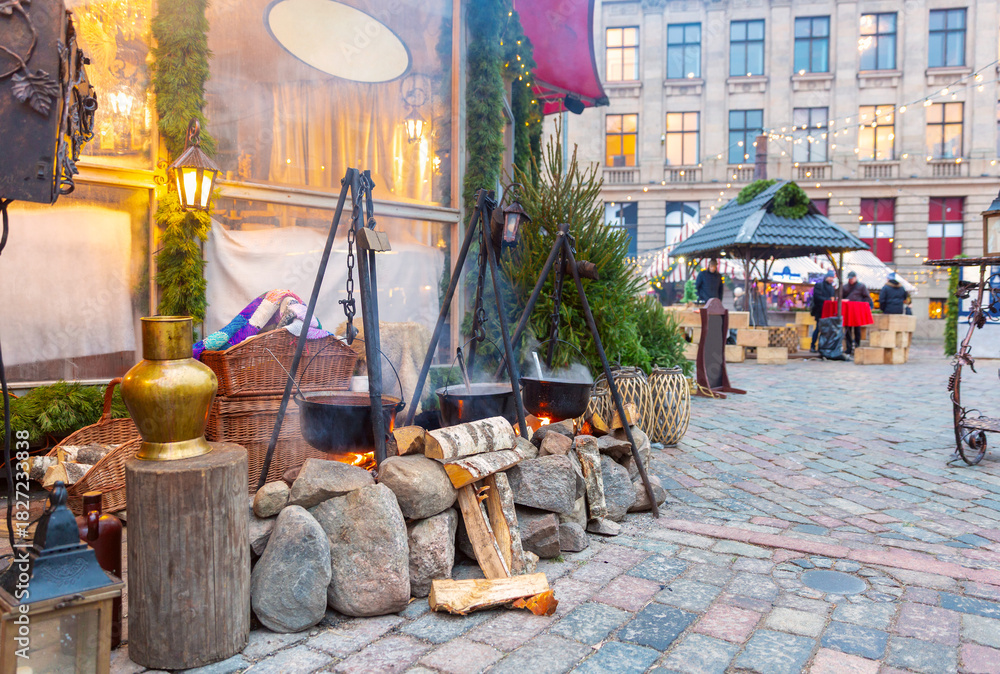Naklejka premium Open-fire cooking pots and holiday decorations at Christmas market in Riga, Latvia
