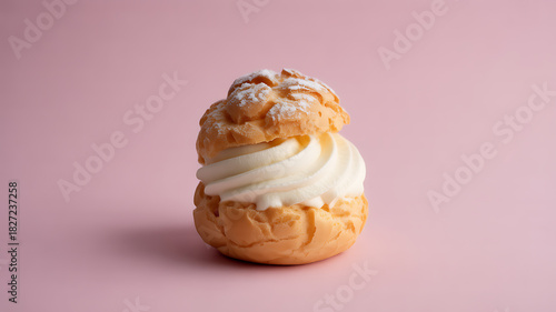 A cream puff filled with whipped cream, dusted with powdered sugar, on a pink background