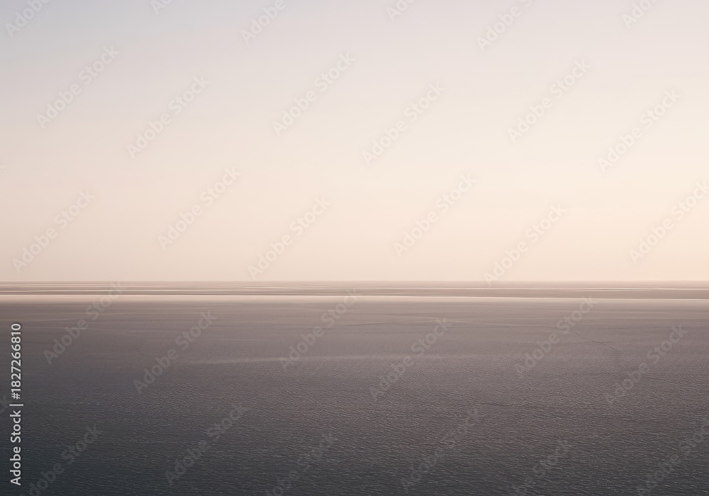 Fototapeta premium An expansive, empty landscape where the flat horizon creates a perfect, unbroken line separating the pale sky from the smooth, endless terrain, subtle, empty, sky